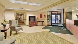 A hotel lobby with a reception desk, seating area, and a television. - Days Inn by Wyndham Cleveland Lakewood (Lakewood)