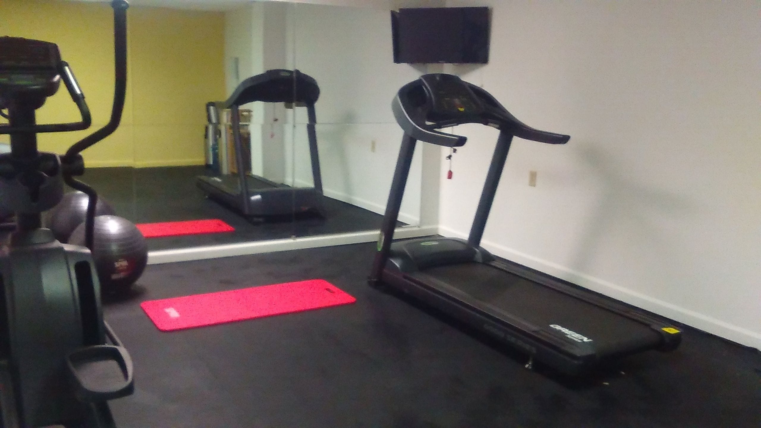 Un gimnasio con cinta de correr, elíptica y bicicleta estática.