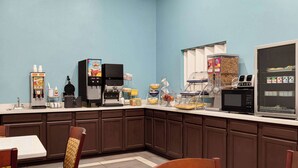 A breakfast area with a coffee machine, microwave, and various food dispensers. - Days Inn by Wyndham Hillsboro (Hillsboro)