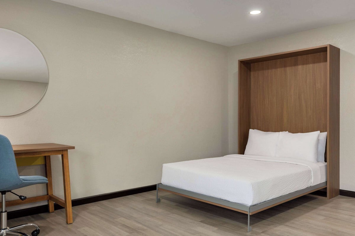 A bedroom with a bed, a desk, and a chair.