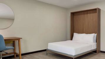 Un dormitorio con una cama, un escritorio y una silla.