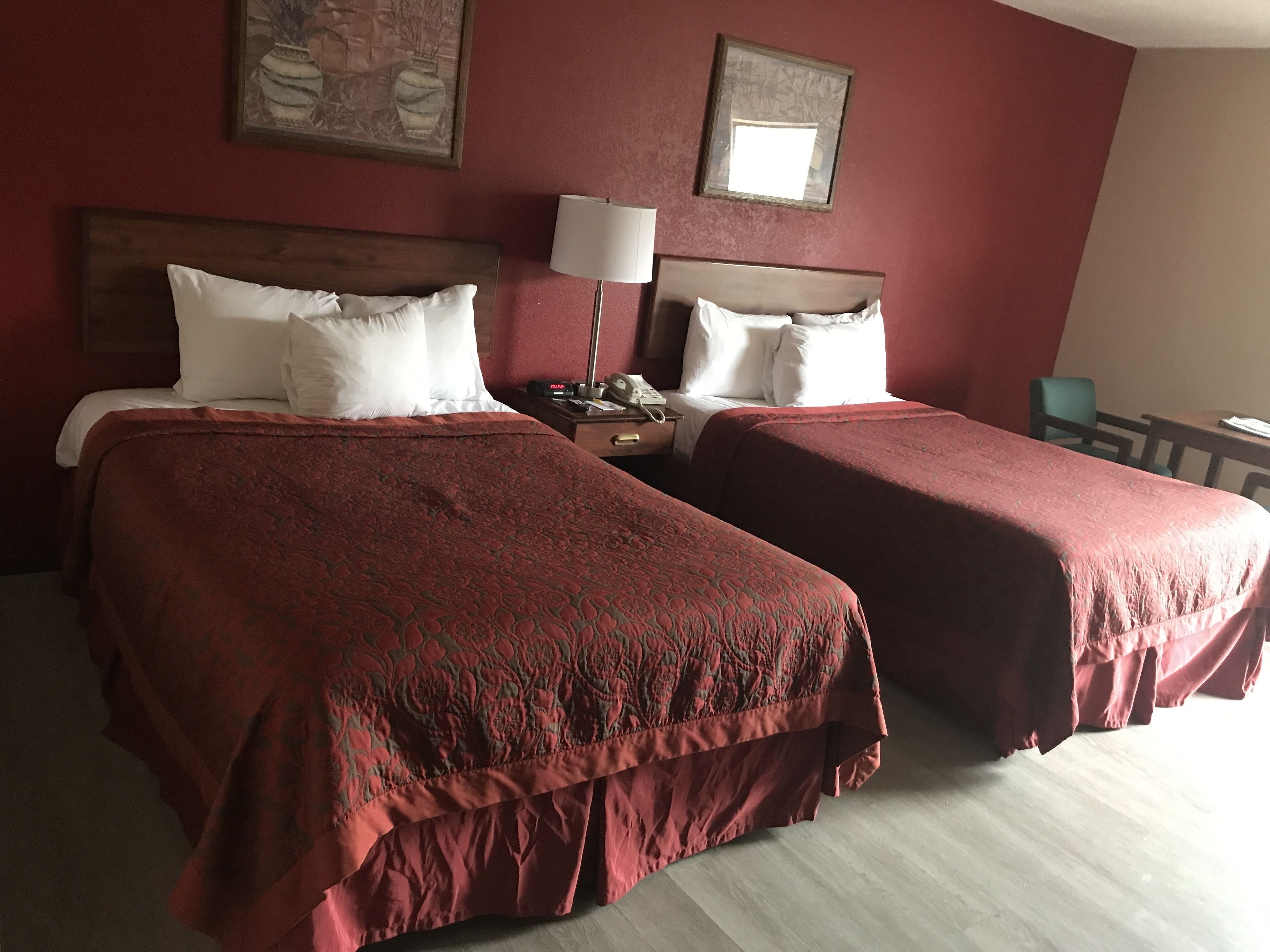 Une chambre d’hôtel avec deux lits, une table de chevet, une lampe et une chaise.