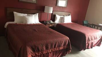 Une chambre d’hôtel avec deux lits, une table de chevet, une lampe et une chaise.