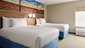 A hotel room with two beds, a large painting on the wall, and a window with an air conditioning unit. - Days Inn by Wyndham Hillsboro (Hillsboro)