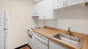 Una cocina con armarios blancos, un lavamanos de acero inoxidable y un horno empotrado.