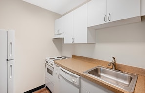 A kitchen with white cabinets, a stainless steel sink, and a built-in oven.