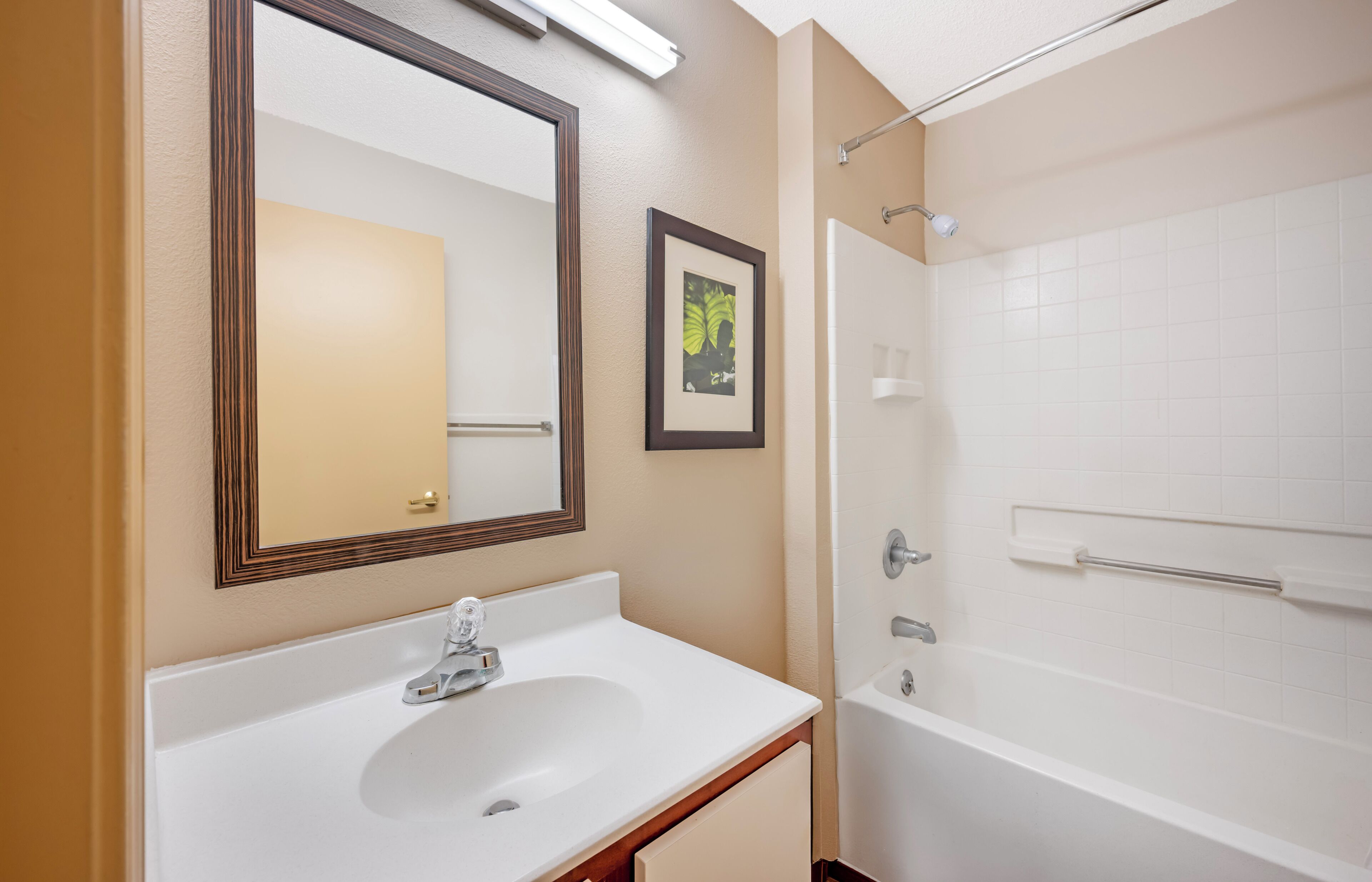 Un baño con lavamanos, espejo y bañera blancos.