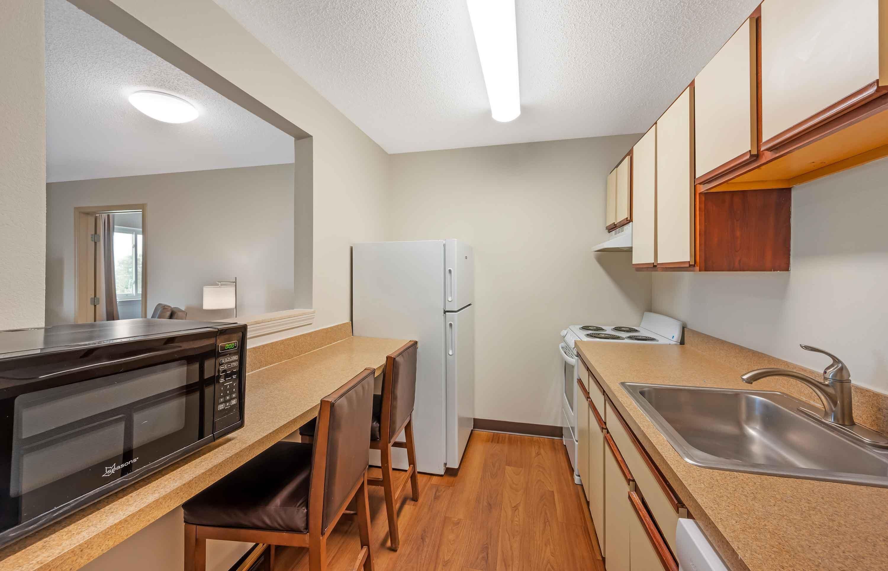 A compact kitchen with a microwave, refrigerator, stove, and sink.