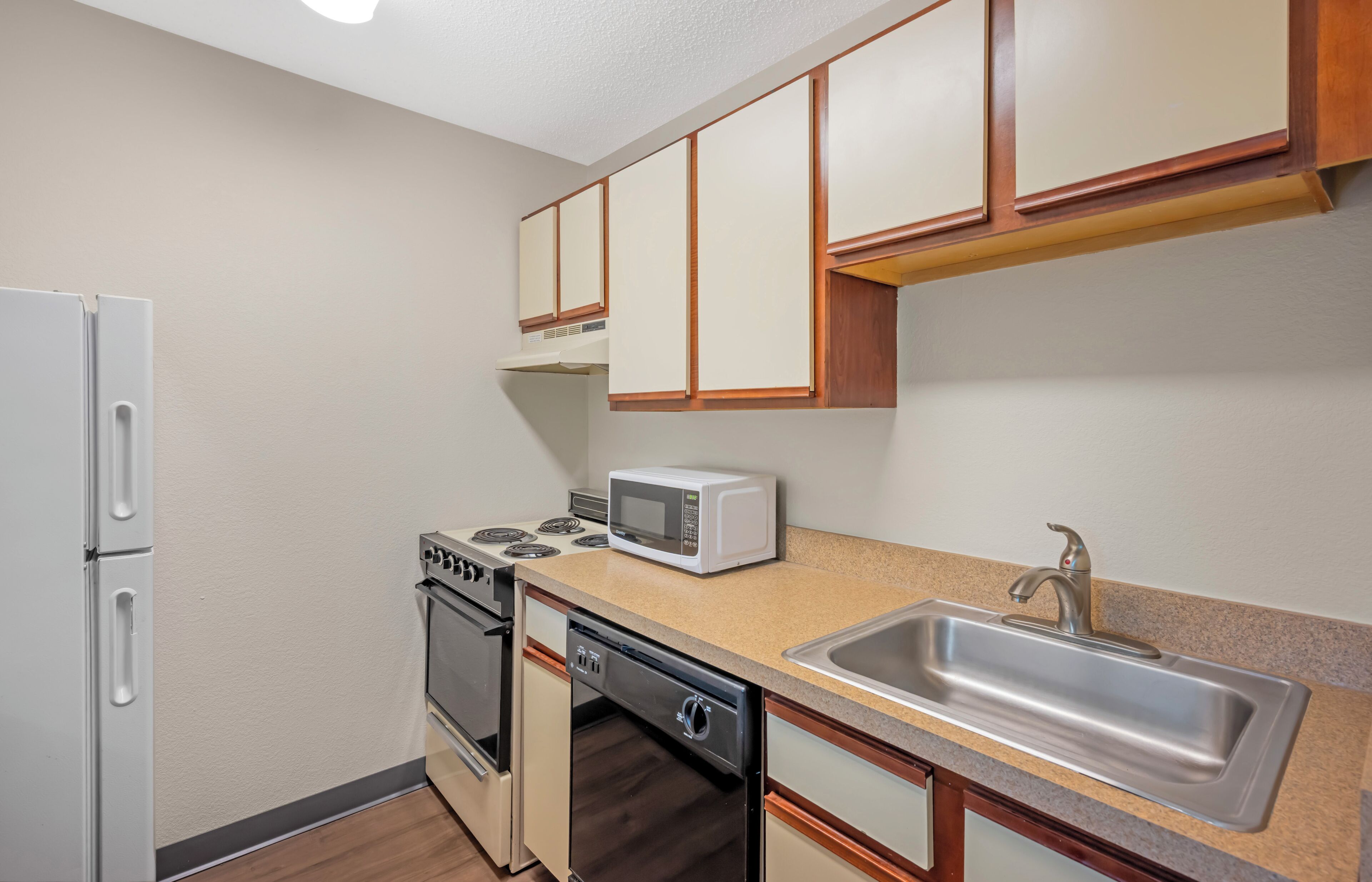 A compact kitchen with a refrigerator, stove, microwave, dishwasher, and sink.