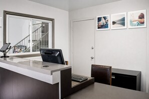 A reception desk with a computer, a telephone, and a keyboard. There is a chair and a small cabinet. - Studio Lodge Springdale Cincinnati  (Cincinnati)
