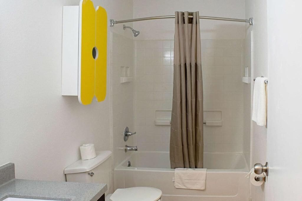Un baño con inodoro, lavamanos, bañera y cortina de ducha.