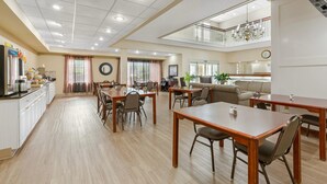 A spacious dining area with wooden tables and chairs, a kitchen area with white cabinets, and a balcony with a railing. - Quality Inn & Suites Bellville - Mansfield (Bellville)