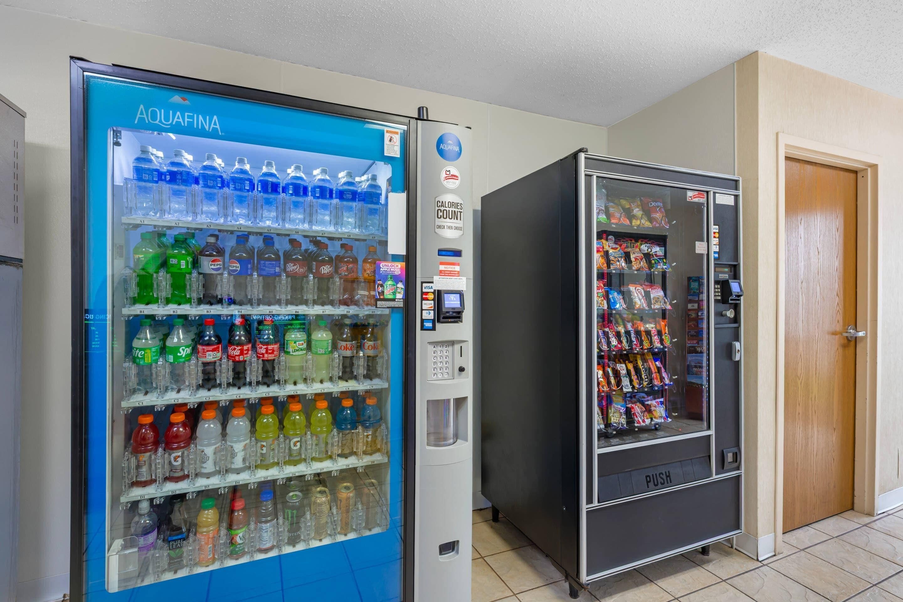 Two vending machines, one with a blue exterior and the other black, both stocked with beverages and snacks.