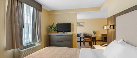 A hotel room with a bed, a desk, a television, and a window with curtains.