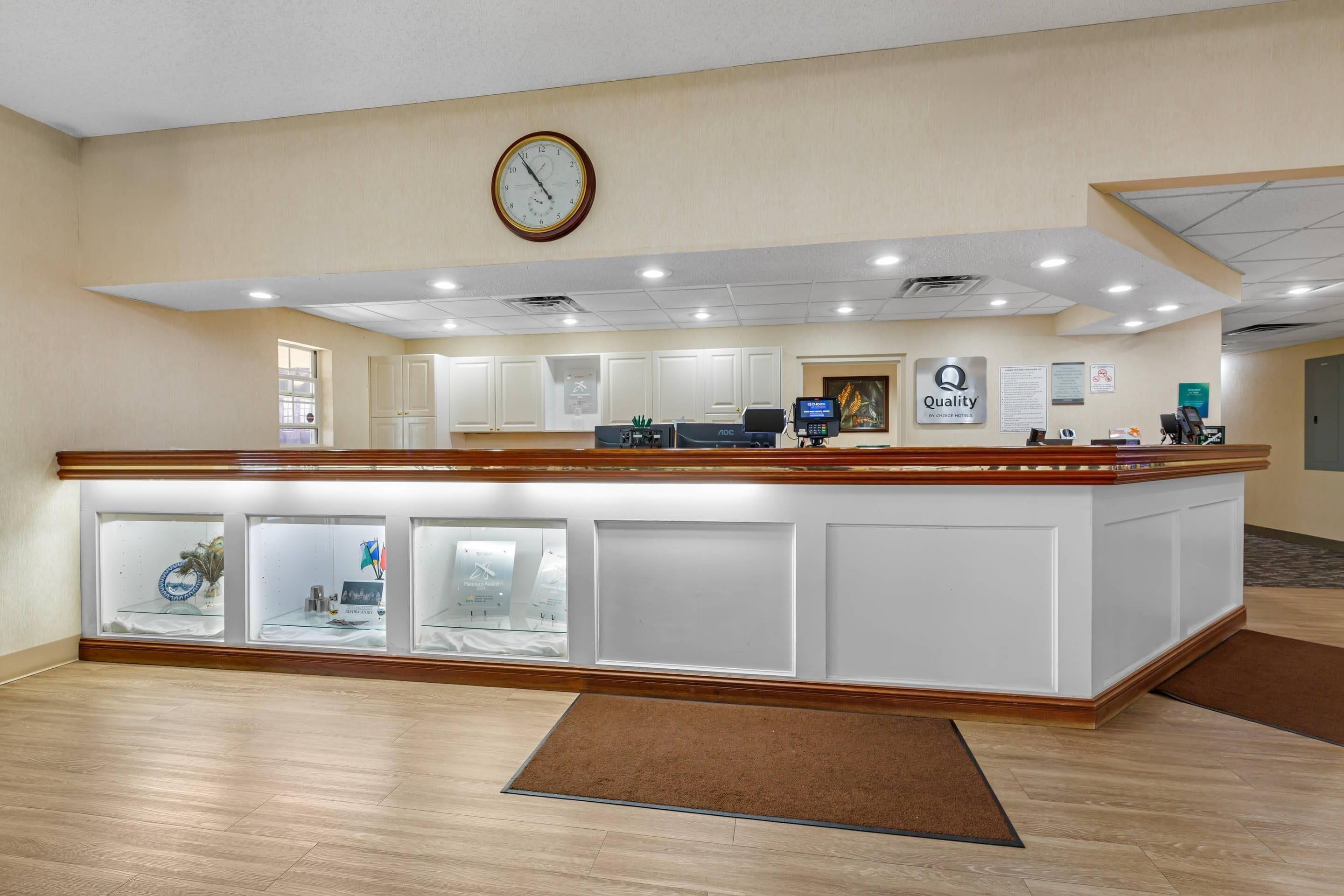 A reception area with a wooden reception desk, a clock, and a 'Quality' sign.