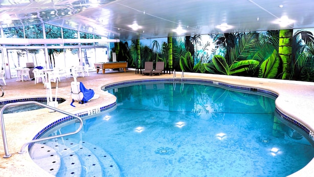 An indoor swimming pool with a tropical mural, lounge chairs, and a seating area. - Quality Inn & Suites Bellville - Mansfield (Bellville)