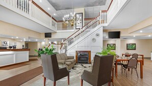 A spacious lobby with a staircase, a fireplace, and a dining area. - Quality Inn & Suites Bellville - Mansfield (Bellville)