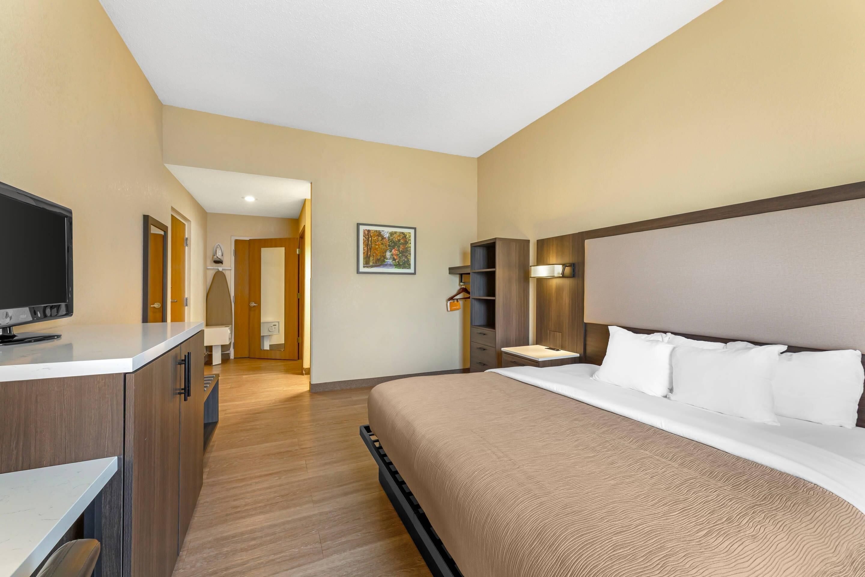 A hotel room with a bed, a TV, a desk, and a wardrobe.