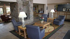 A lobby with a stone fireplace, blue patterned chairs, a coffee table, and a reception desk. - Hampton Inn & Suites Chillicothe (Chillicothe)