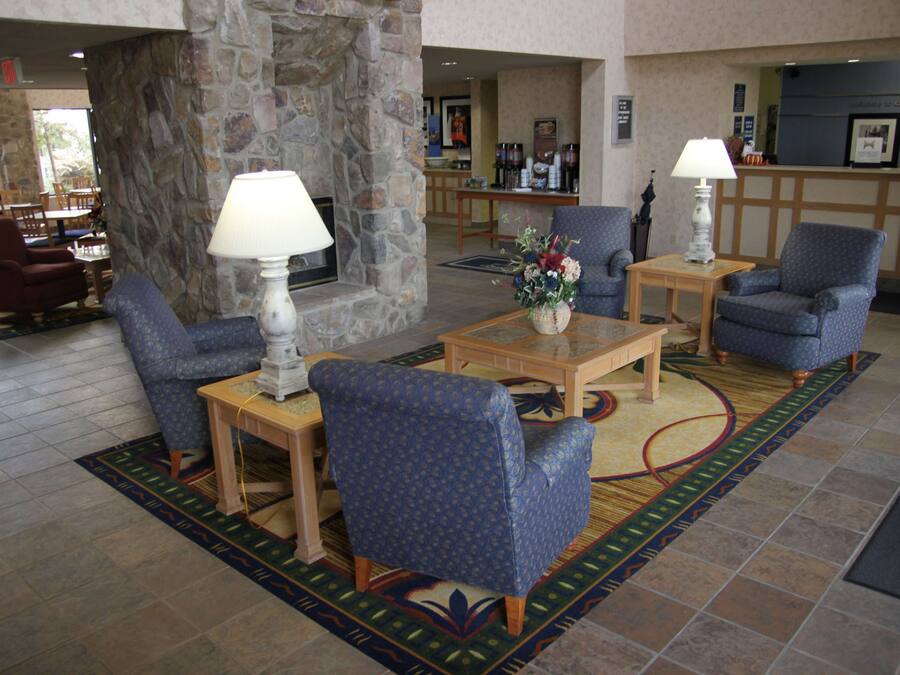 A lobby with a stone fireplace, blue patterned chairs, a coffee table, and a reception desk.