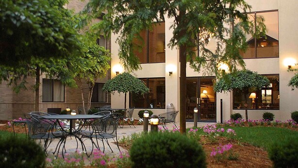 An outdoor patio area with tables and chairs, surrounded by greenery and decorative lighting. - Hampton Inn & Suites Chillicothe (Chillicothe)