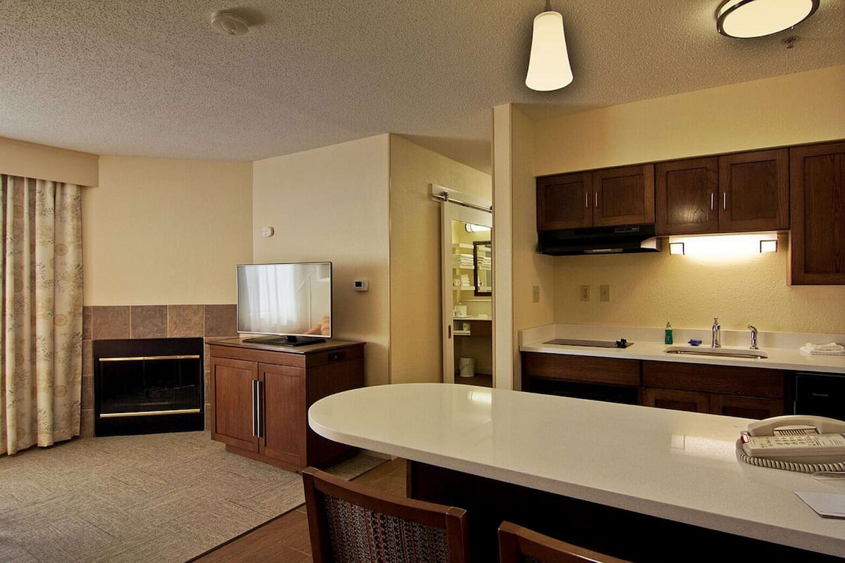A compact kitchen with a built-in stove, a dining area with a white table, and wooden cabinets.