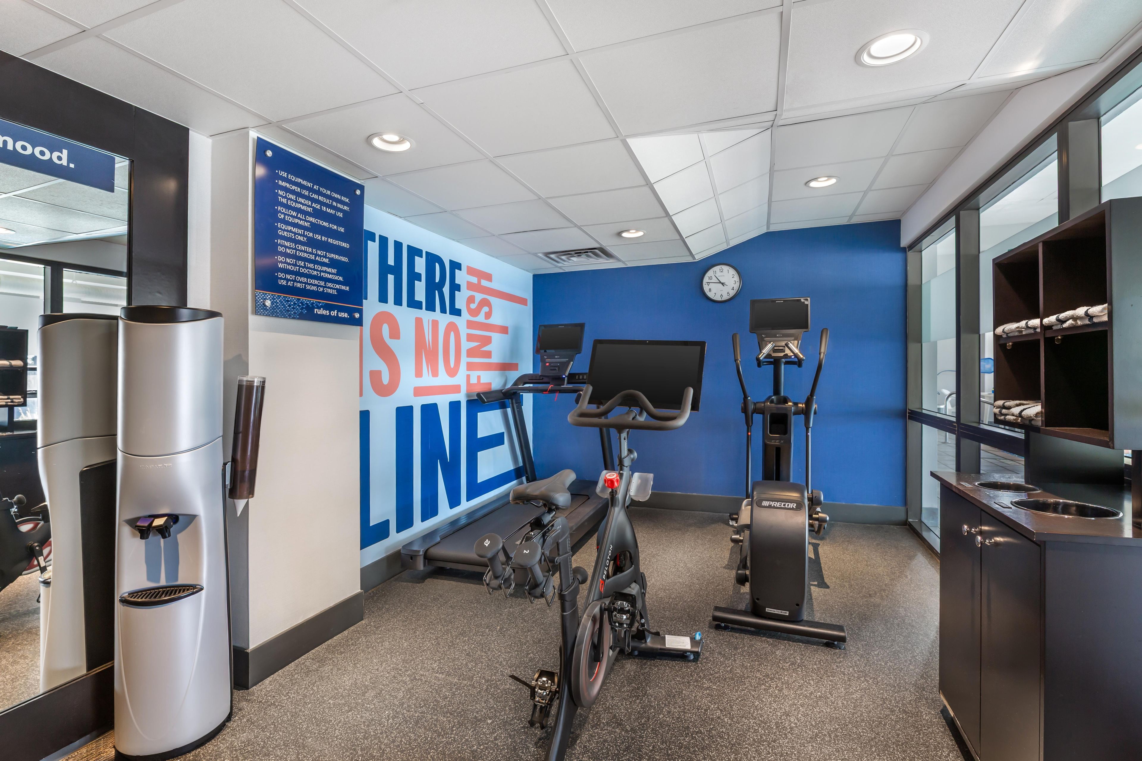 A gym with exercise equipment, a wall with safety instructions, and a clock.