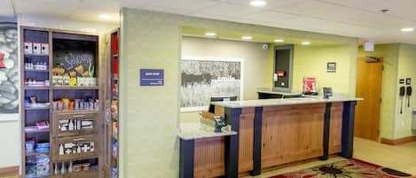 Et hotelreceptionsområde med en reception, et skilt der siger 'Velkommen til Wooster', et skilt der siger 'Suite Shop' og en plakat med ordet 'Smil'.
