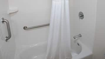 A white bathtub with a shower curtain, grab bars, and a handheld showerhead.
