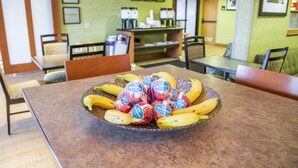 Un comedor con una mesa dispuesta, con un frutero que contiene plátanos y hámsters envasados.