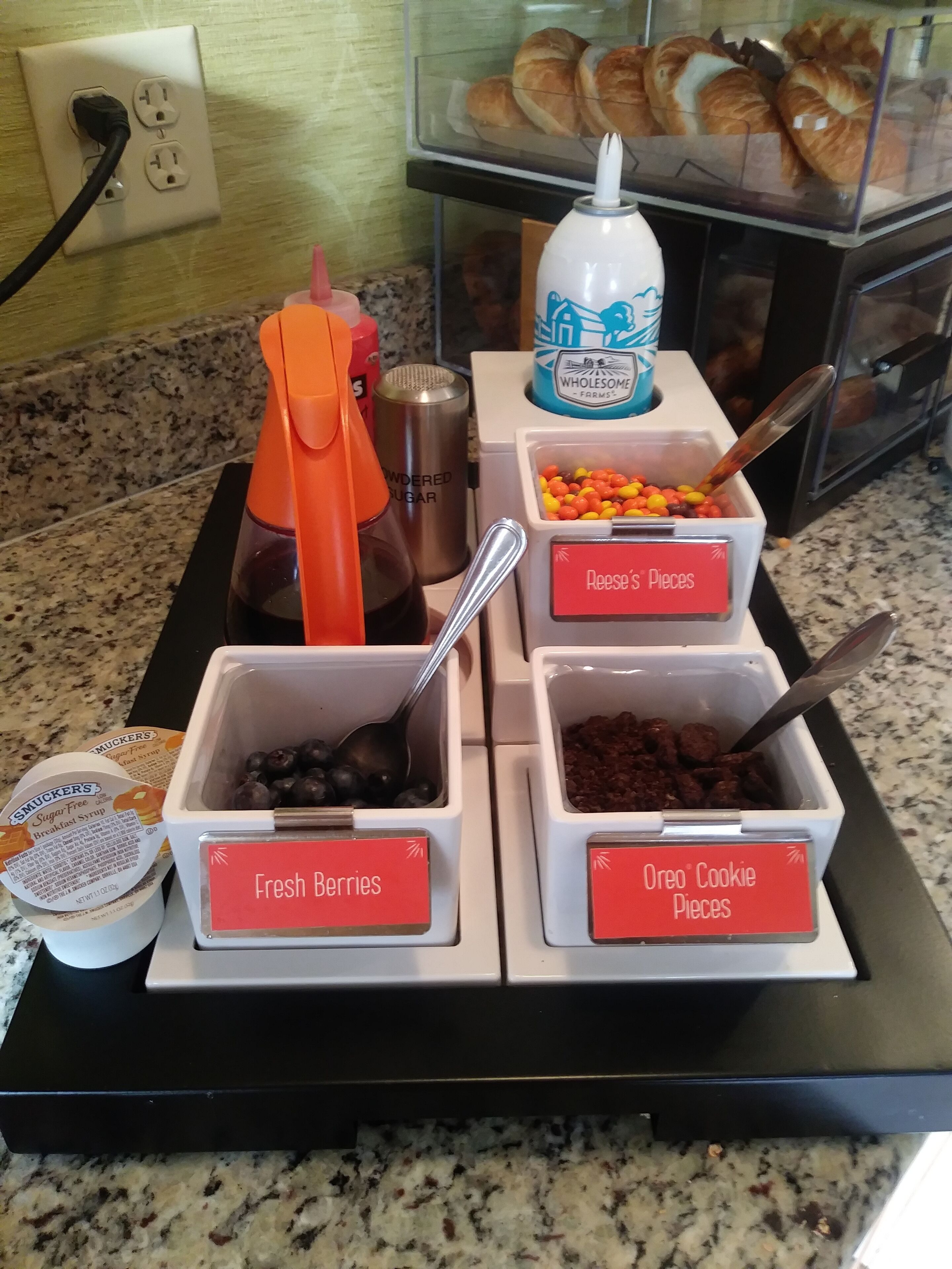 Een ontbijtbuffet met bakken met verse bessen, stukjes Oreo-koekjes en andere lekkernijen.
