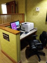 Centro de negocios con computadora, impresora y dos sillas de oficina.