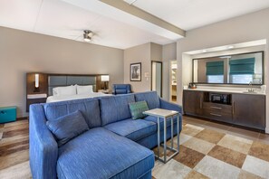A hotel room with a sectional sofa, a bed, a desk, a kitchenette, and a bathroom. - Hampton Inn Wooster (Wooster)