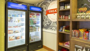 Zona de exhibición de aperitivos y bebidas, con congeladores refrigerados y estantes llenos de diferentes opciones.