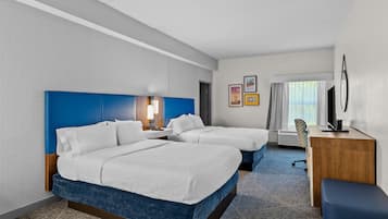 A hotel room with two beds, a desk, a chair, and a large window.