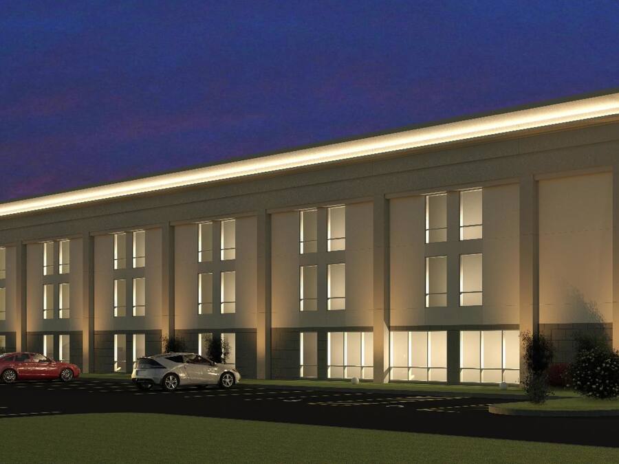 A modern hotel with a large parking lot, a covered entrance, and a well-lit facade.