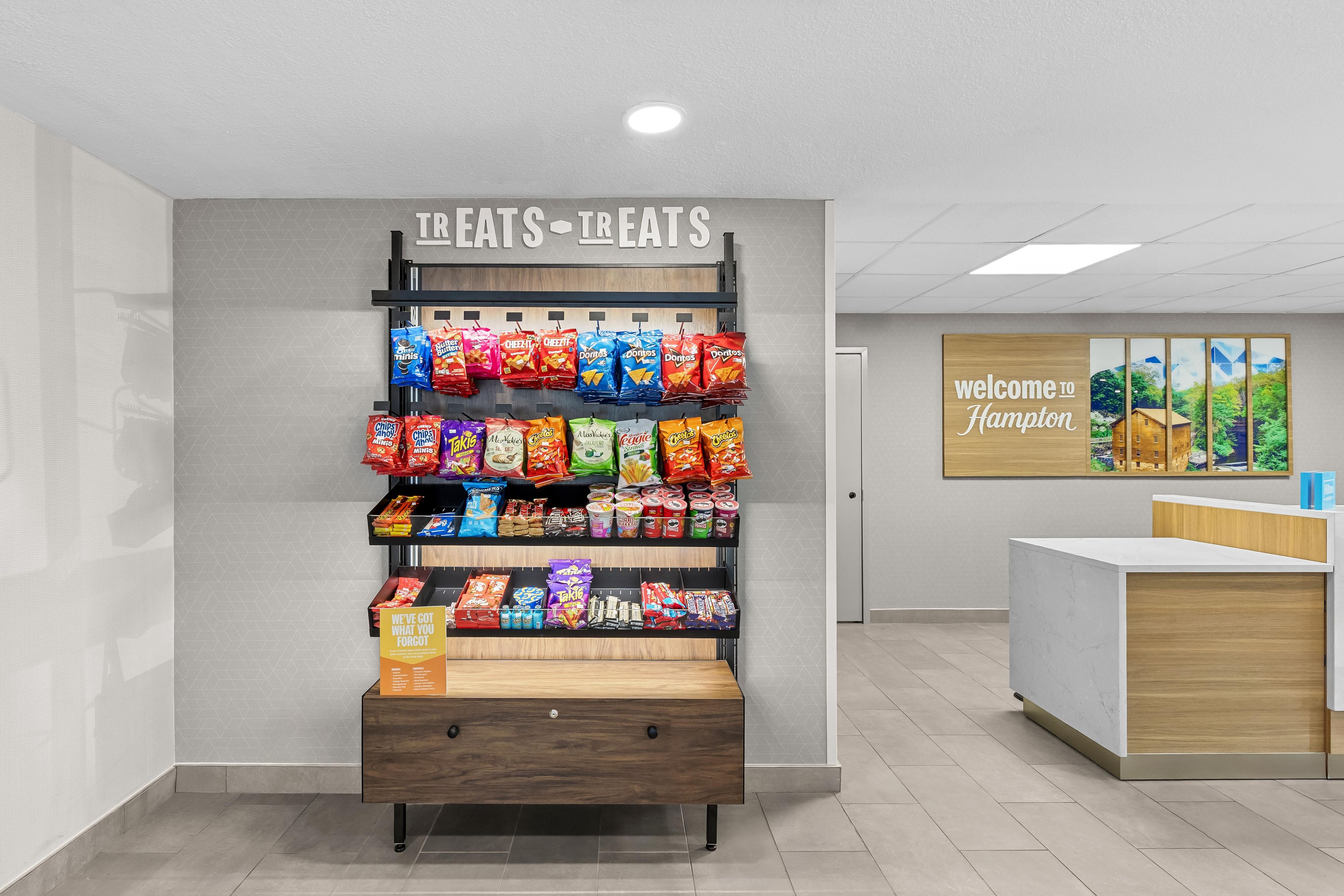 Eine Theke mit Snacks in der Hotelhalle, über ihr ein Schild mit der Aufschrift 'LEATS-TREATS'.