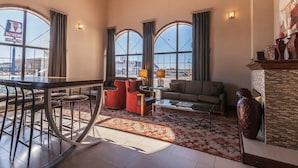 A spacious living area with a bar, red chairs, a sofa, and a large window offering a view of the city. - Quality Inn & Suites Owasso US-169 (Owasso)