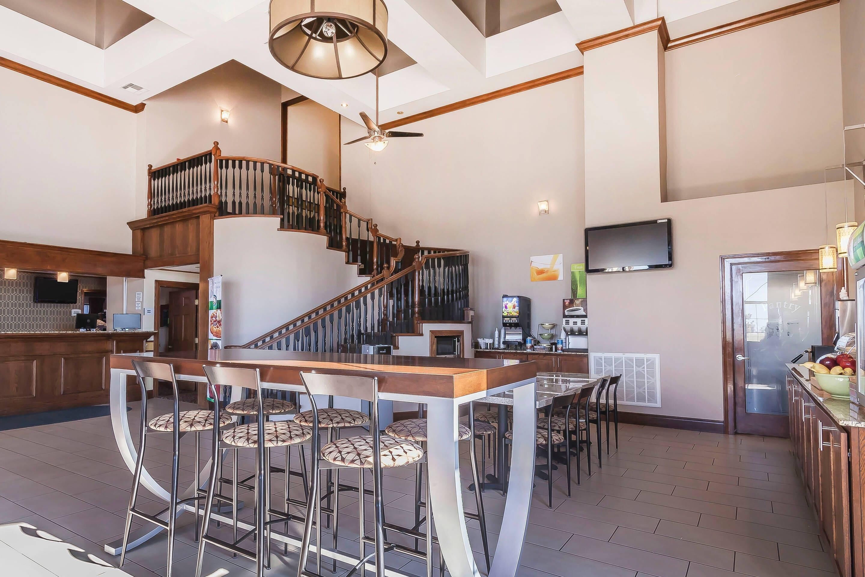 A spacious kitchen with a central island, bar stools, and a staircase leading to an upper level.