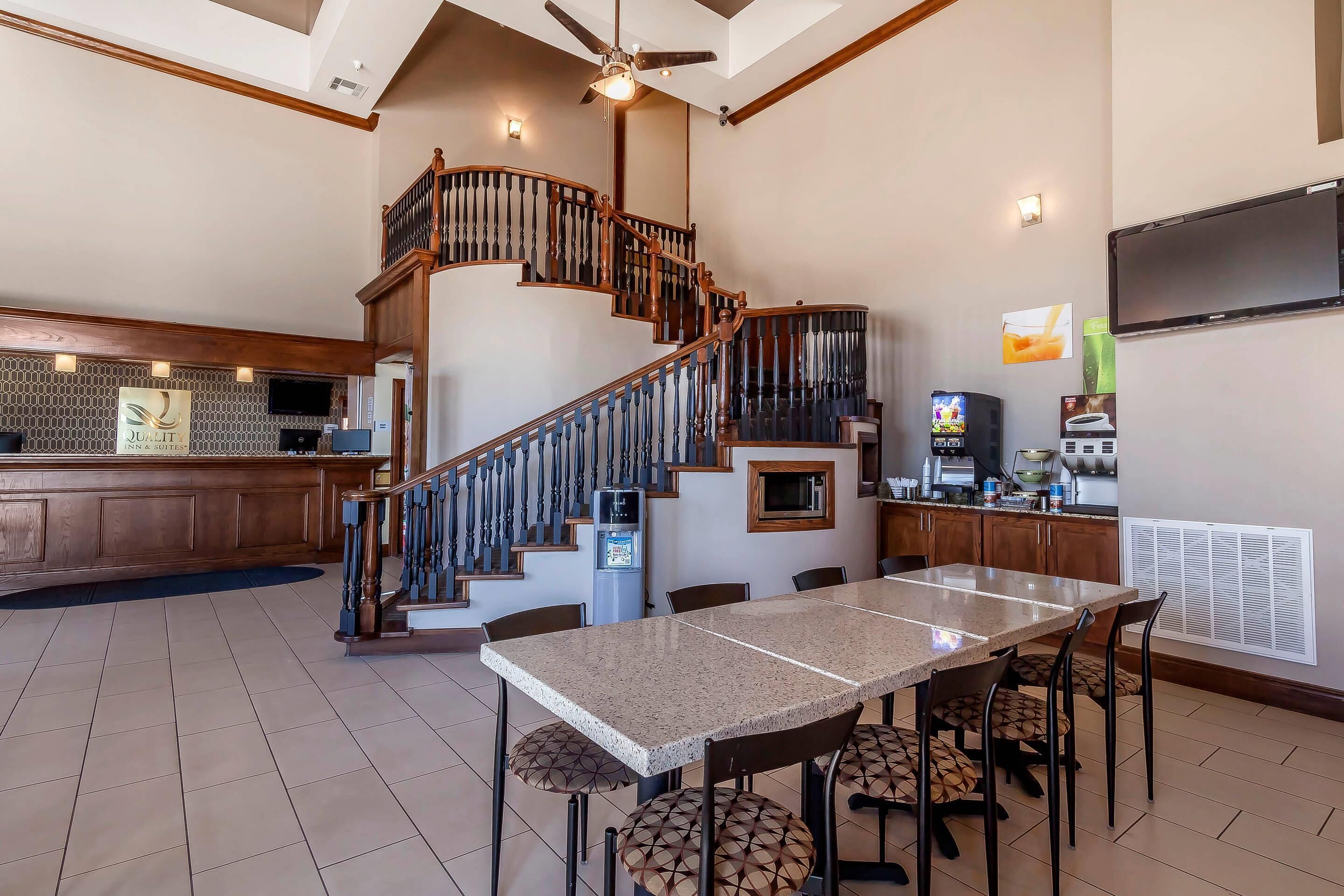 A spacious kitchen with a large island, a dining area with a long table and chairs, and a spiral staircase.