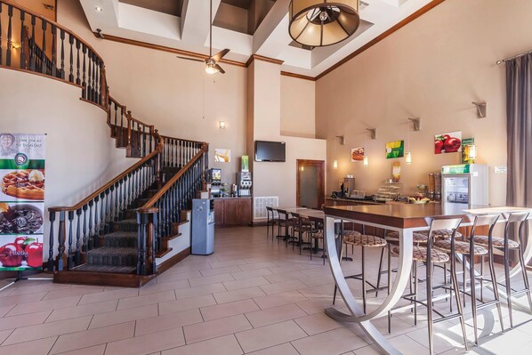 A spacious kitchen with a central island, a dining area with bar stools, a staircase with wooden railings, and a ceiling fan.