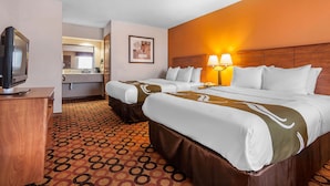 A hotel room with two beds, a TV, a bathroom, and a patterned carpet. - Quality Inn & Suites Owasso US-169 (Owasso)