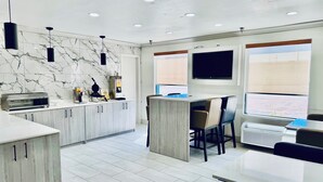 A modern kitchen with marble backsplash, built-in appliances, and a dining area with chairs and a table. - Baymont by Wyndham Ardmore I-35 (Ardmore)