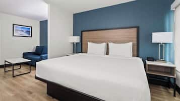 Une chambre d’hôtel avec un grand lit, un bureau, une chaise et une table de chevet avec une lampe.
