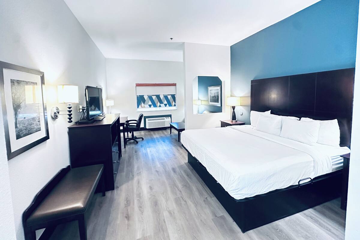 Una habitación de hotel con cama, escritorio, silla y un ventanal grande.