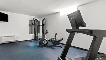 A gym with a treadmill, elliptical, and weight machines.