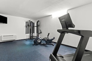 Un gimnasio con cinta de correr, elíptica y máquinas de pesas.