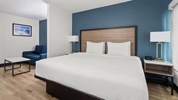 A hotel room with a large bed, a desk, a chair, and a nightstand.