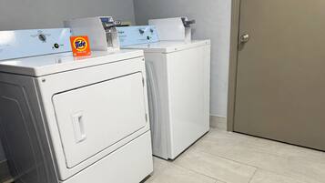 Une buanderie équipée de deux machines à laver et deux sèche-linge superposés, d’une boîte de lessive Tide et d’une porte.
