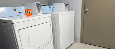 A laundry room with two stacked washers and dryers, a Tide detergent box, and a door.